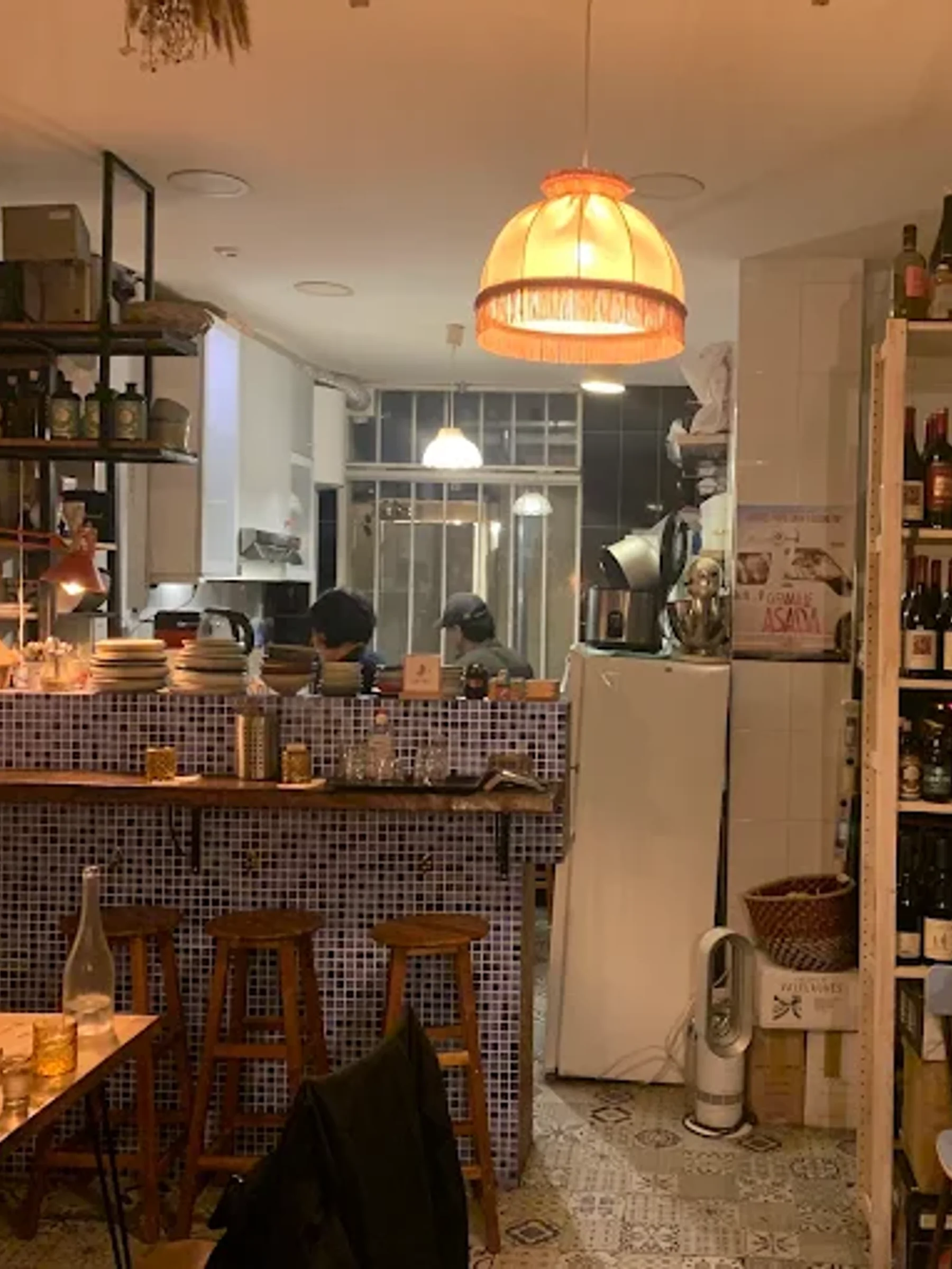 Intérieur de Subaco : comptoir en mosaïque bleue, cuisine ouverte et étagères de bouteilles